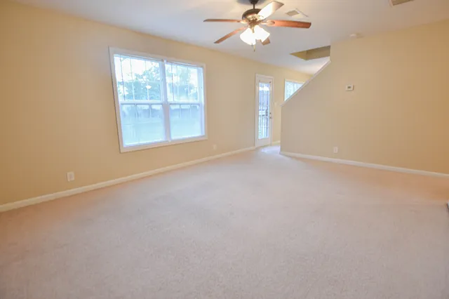 an empty room with windows and fan