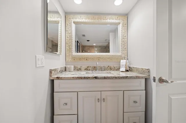 a bathroom with a granite countertop sink and a mirror