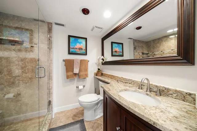a bathroom with a granite countertop sink mirror vanity and toilet