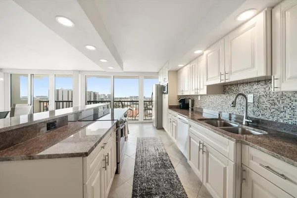 a large kitchen with granite countertop a large counter top appliances a sink and cabinets