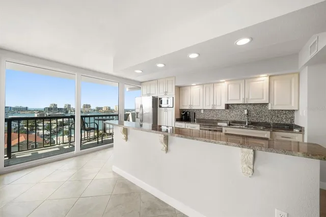 a large white kitchen with kitchen island a large counter top space a sink stainless steel appliances and cabinets