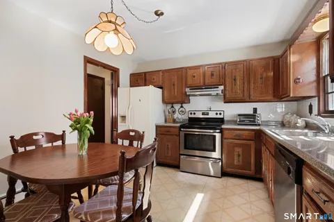 a kitchen with stainless steel appliances kitchen island a table chairs in it and wooden floors