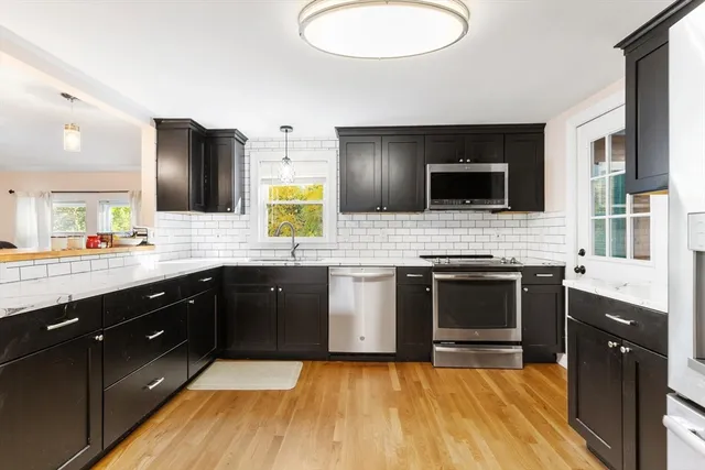 a large kitchen with a sink and a stove top oven with wooden floor