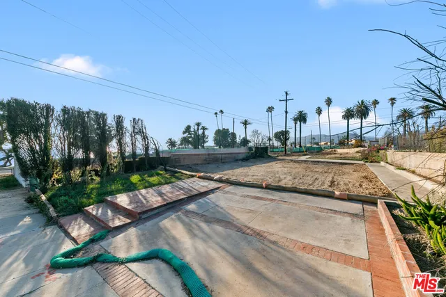 a view of a swimming pool with a yard and potted plants