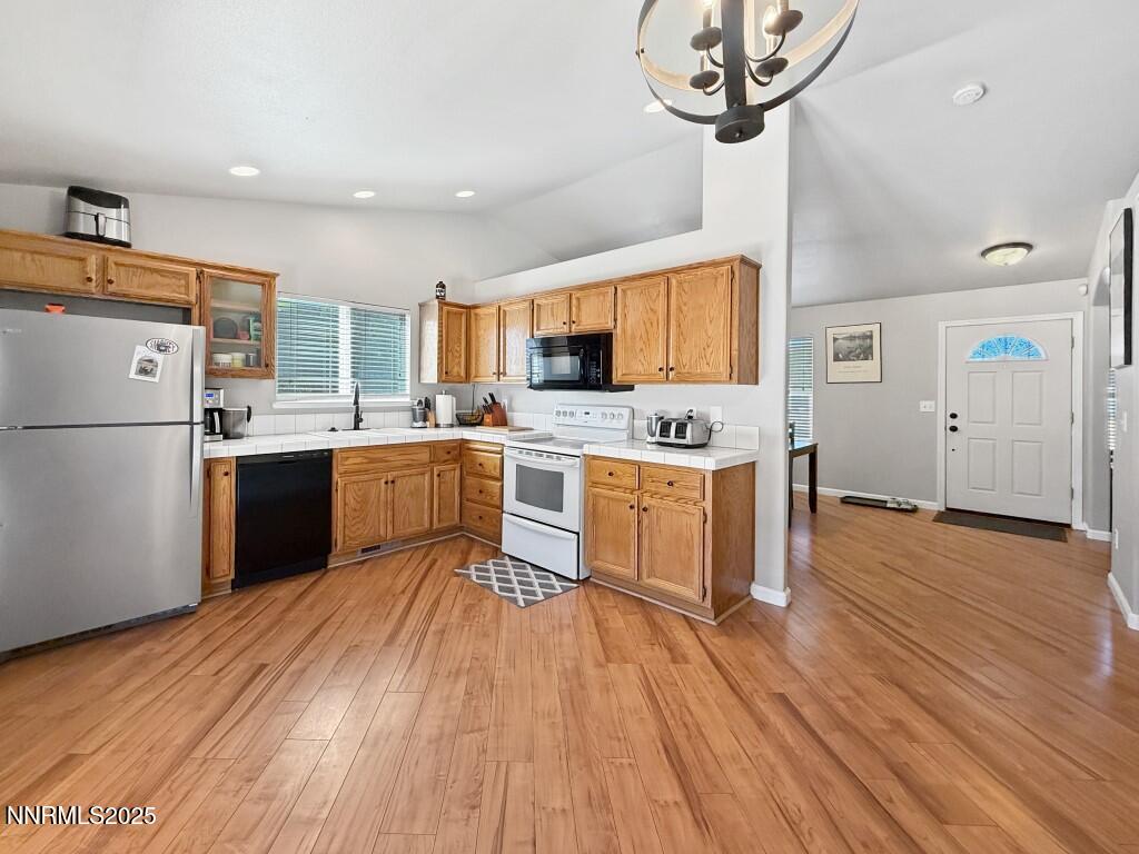 2119 Fort Bridger Road Fernley, NV 89408 - Photo 6 of 18 a kitchen with stainless steel appliances a stove a sink dishwasher a refrigerator with white cabinets and wooden floor