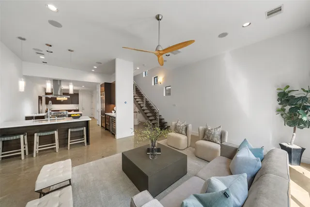 a living room with furniture kitchen view and a wooden floor