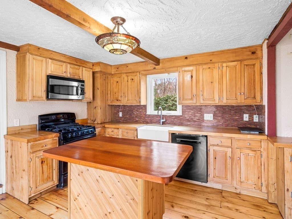 775 Shore Road Bourne, MA 02559 - Photo 10 of 42 a kitchen with stainless steel appliances wooden cabinets a stove a sink a microwave and a refrigerator