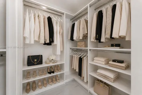 a view of walk in closet with clothes and shoes