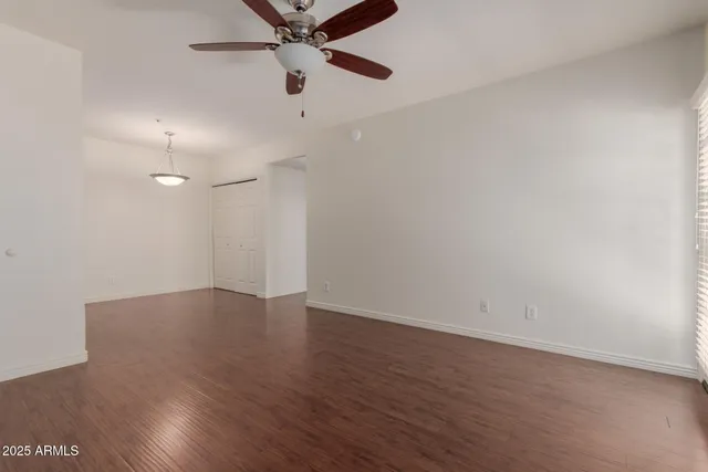 an empty room with wooden floor fan and windows