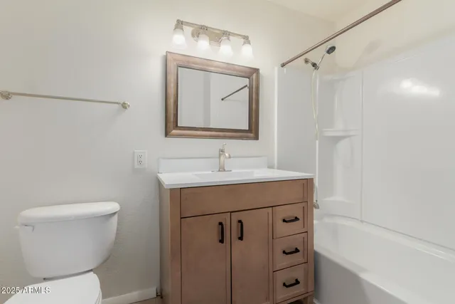 a bathroom with a toilet a sink a mirror a shower and vanity