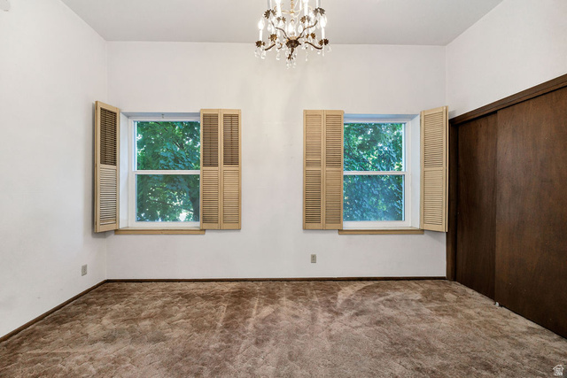 299 West Center Street, Unit 2 Logan, UT 84321 - Photo 22 of 46 Room featuring two windows with louvered shutters, a built-in closet with dark wood sliding doors, and a decorative chandelier