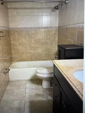 a bathroom with a granite countertop bathtub sink vanity mirror and toilet