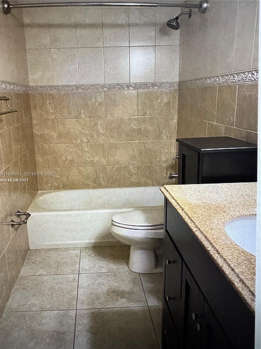 7130 Northwest 179th Street, Unit 108 Hialeah, FL 33015 - Photo 11 of 11 a bathroom with a granite countertop bathtub sink vanity mirror and toilet