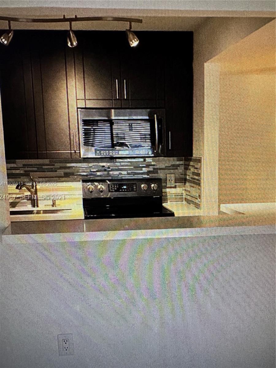 7130 Northwest 179th Street, Unit 108 Hialeah, FL 33015 - Photo 4 of 11 a kitchen with stainless steel appliances wooden cabinets and a stove top oven
