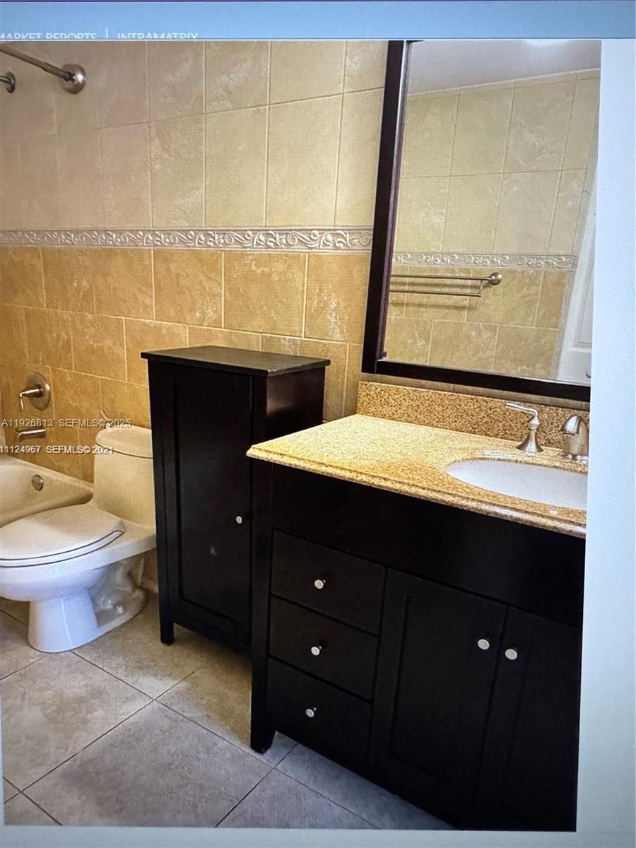 7130 Northwest 179th Street, Unit 108 Hialeah, FL 33015 - Photo 10 of 11 a bathroom with a sink a toilet and a mirror