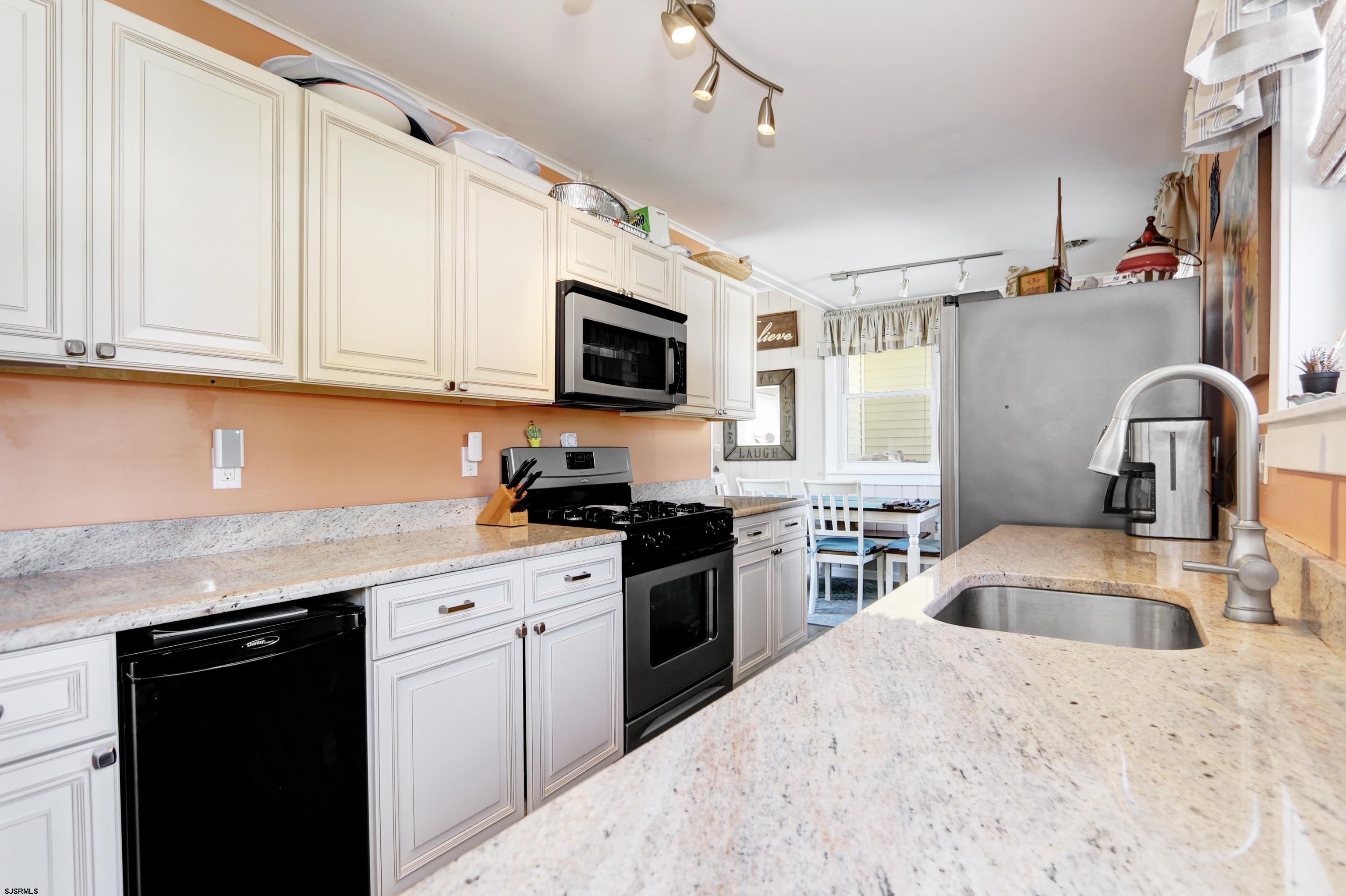 34 North Shore Road Marmora, NJ 08223 - Photo 9 of 37 a kitchen with granite countertop a sink dishwasher stove and microwave with wooden floor