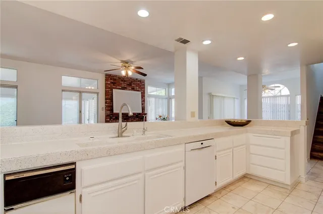 a kitchen with stainless steel appliances kitchen island granite countertop a refrigerator sink and white cabinets