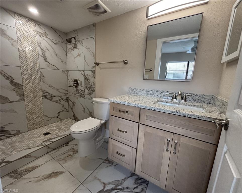 5327 Summerlin Road, Unit 2709 Fort Myers, FL 33919 - Photo 10 of 11 a bathroom with a granite countertop toilet a sink and a mirror