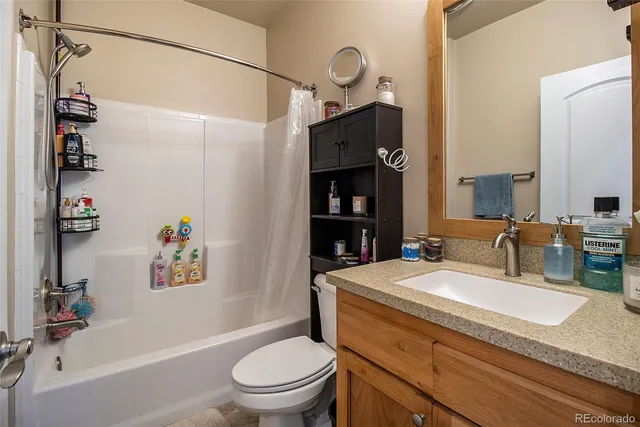 a bathroom with a granite countertop sink a toilet and shower