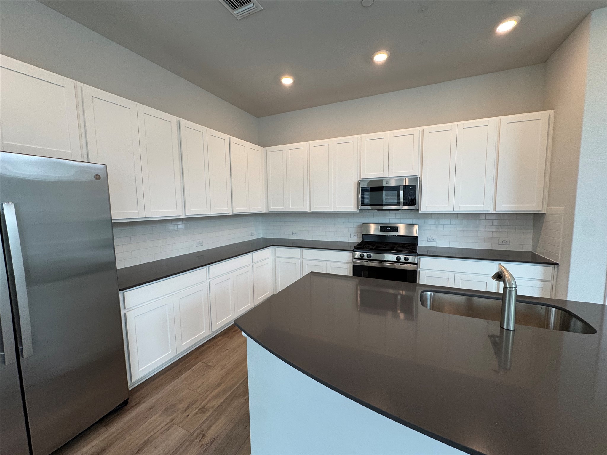 3000 Chisholm Trail Road, Unit 103 Round Rock, TX 78681 - Photo 7 of 32 Kitchen with stainless steel appliances, tasteful backsplash, white cabinetry, dark wood-style floors, and recessed lighting