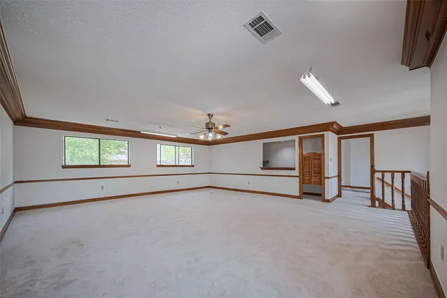 an empty room with windows and ceiling fan