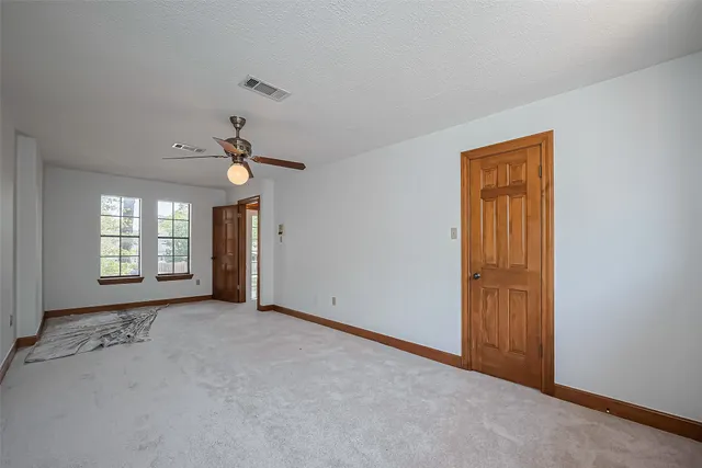 a view of an empty room with chandelier fan