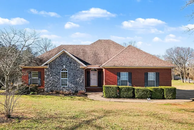 a front view of house with yard and trees in the background