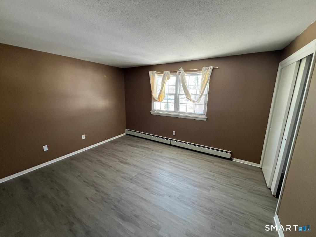 633 Center Street, Unit E Manchester, CT 06040 - Photo 12 of 15 an empty room with wooden floor and windows