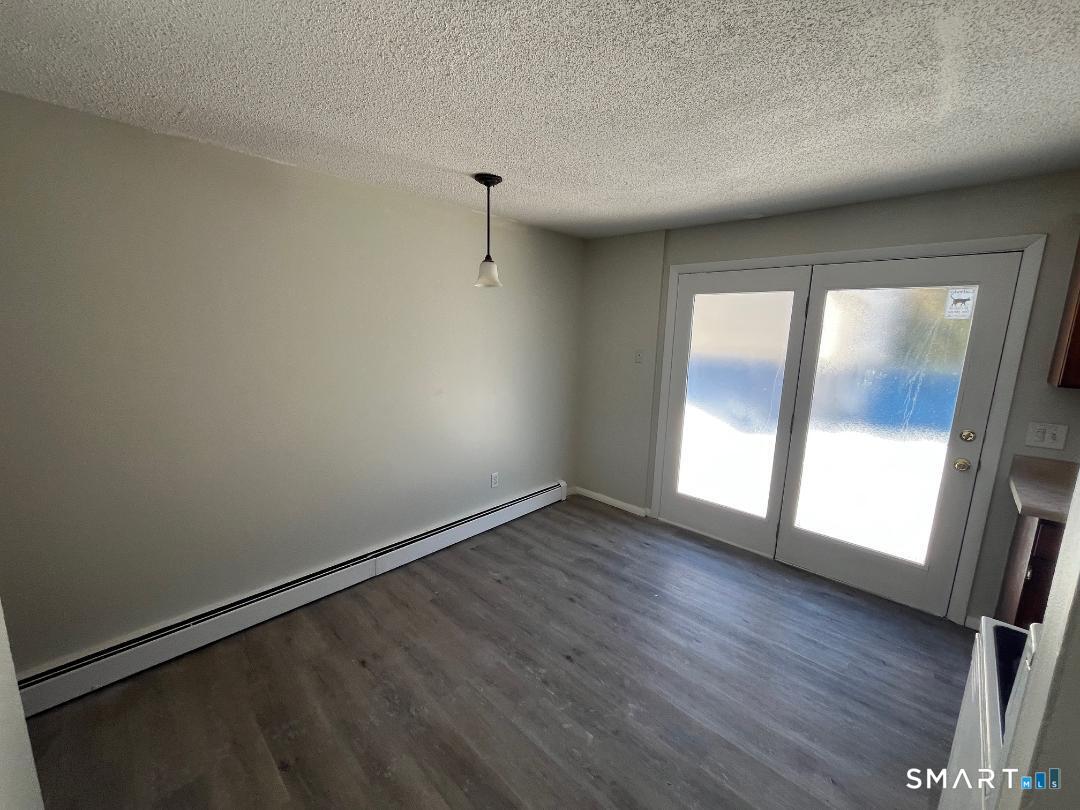 633 Center Street, Unit E Manchester, CT 06040 - Photo 6 of 15 an empty room with wooden floor and windows
