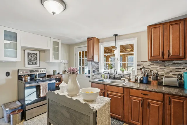 a kitchen with stainless steel appliances granite countertop a stove a sink dishwasher a refrigerator and a dining table with wooden cabinet