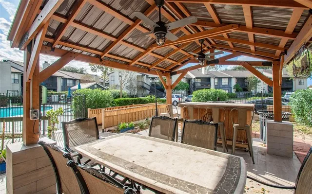 a view of a patio with a table and chairs under an umbrella with a barbeque