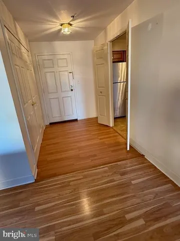 a view of an empty room with wooden floor and a ceiling fan