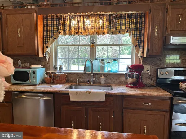a kitchen with stainless steel appliances granite countertop a sink a stove and wooden cabinets