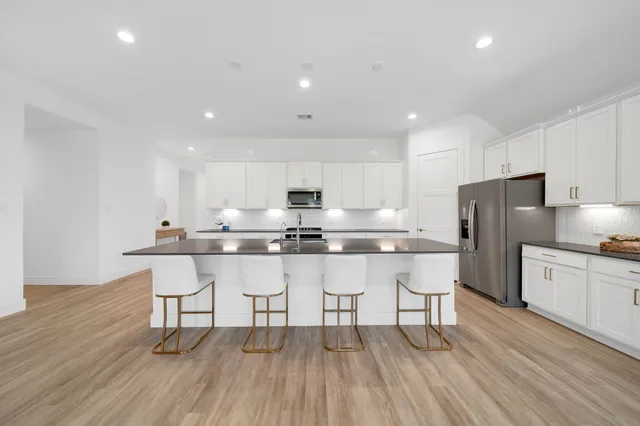 a kitchen with stainless steel appliances a dining table chairs microwave and sink