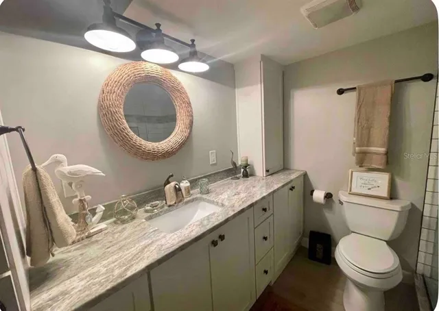 a bathroom with a granite countertop toilet sink and mirror