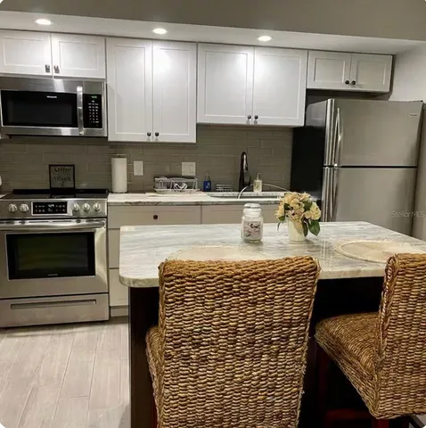 a kitchen with stainless steel appliances kitchen island granite countertop a stove refrigerator sink and microwave