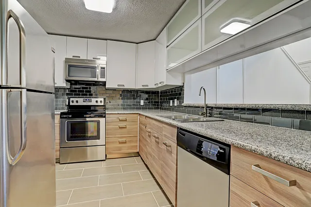 a kitchen with stainless steel appliances granite countertop a stove a sink and a refrigerator