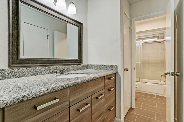 a bathroom with a granite countertop sink and a mirror
