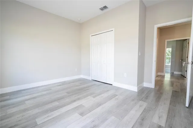 a view of an empty room with wooden floor and closet