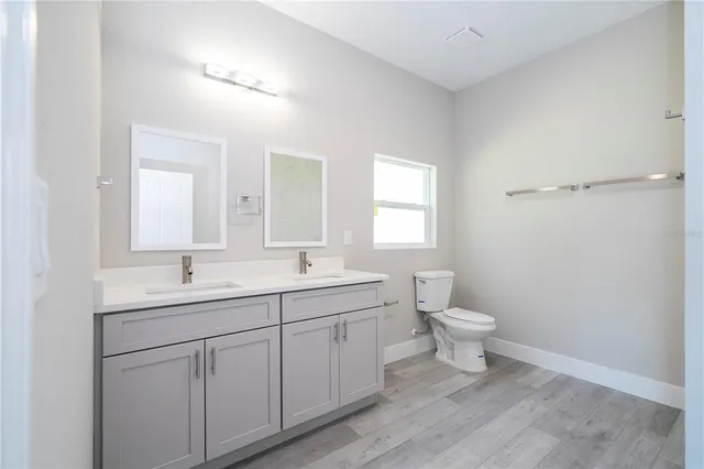 a bathroom with a toilet a sink a mirror and a window