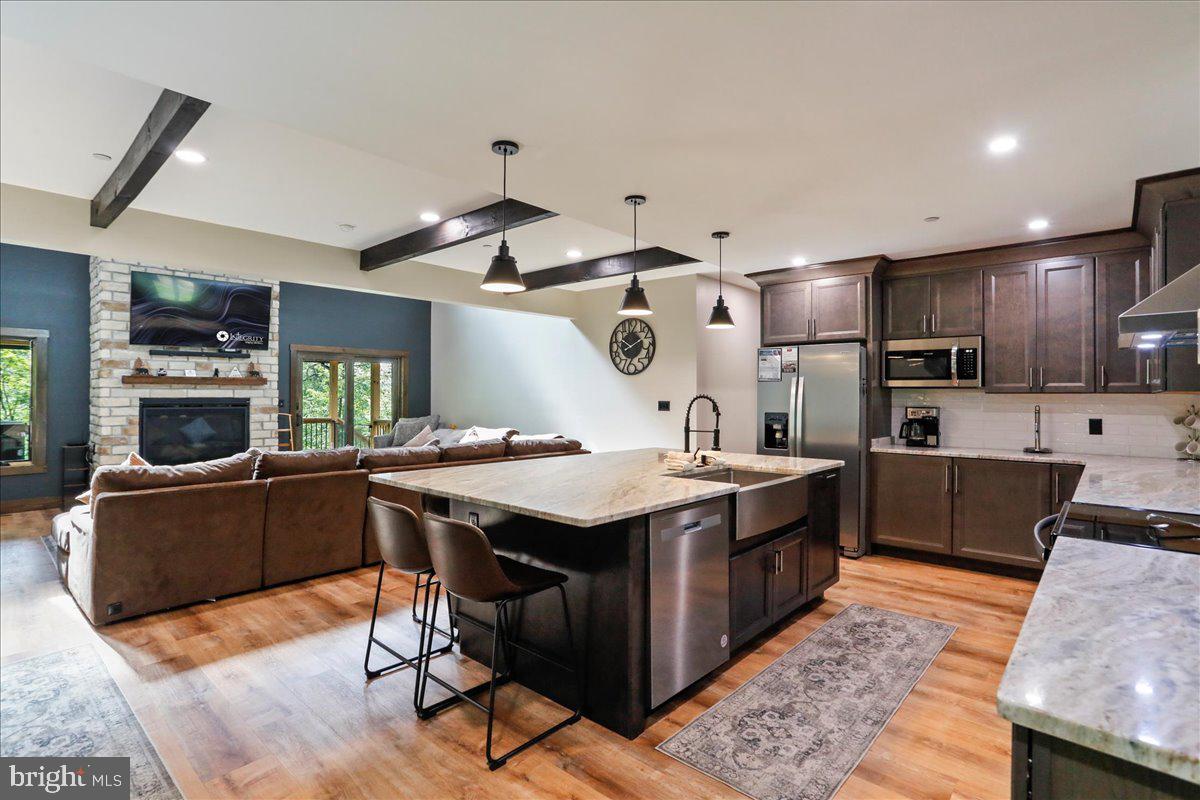 a kitchen with stainless steel appliances granite countertop wooden cabinets a sink dishwasher a stove and a refrigerator with wooden floor