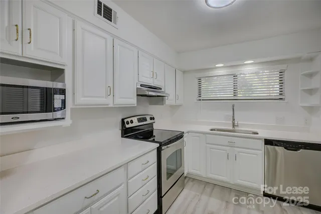 a kitchen with cabinets appliances a sink and a window