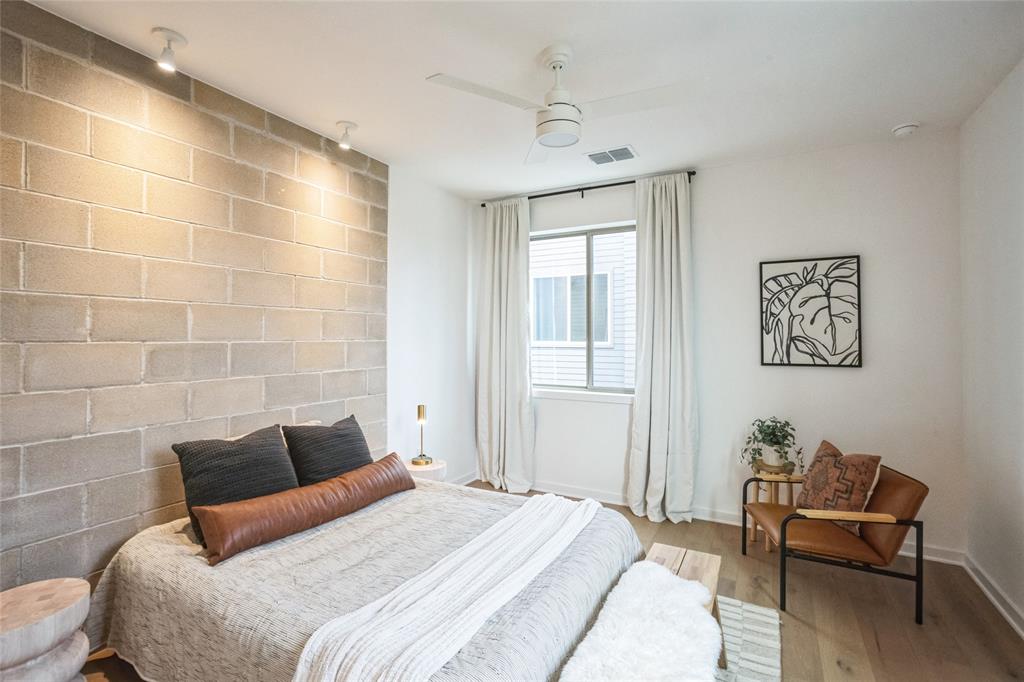 700 Denson Drive, Unit 1102 Austin, TX 78752 - Photo 14 of 30 a bedroom with a bed and a chair