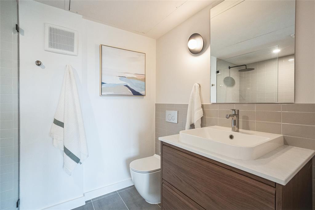 700 Denson Drive, Unit 1102 Austin, TX 78752 - Photo 19 of 30 a bathroom with a sink a toilet and a mirror