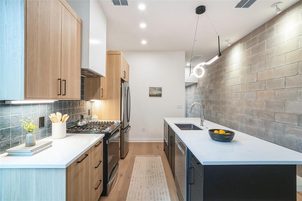 700 Denson Drive, Unit 1102 Austin, TX 78752 - Photo 6 of 30 a kitchen that has a sink a stove and a wooden floor