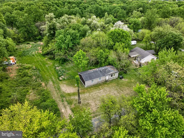 an aerial view of residential house with outdoor space and trees all around