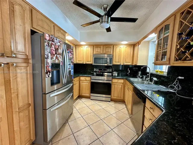 a kitchen with stainless steel appliances granite countertop a refrigerator a sink dishwasher a stove and white cabinets with wooden floor