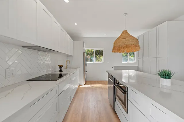 a kitchen with stainless steel appliances granite countertop a sink a stove and a wooden floors