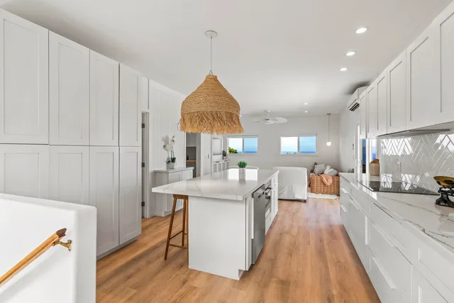 a view of a kitchen with kitchen island a counter top space a sink a stove and a wooden floors