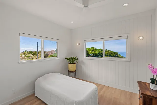 a white bed sitting in a bedroom next to a window